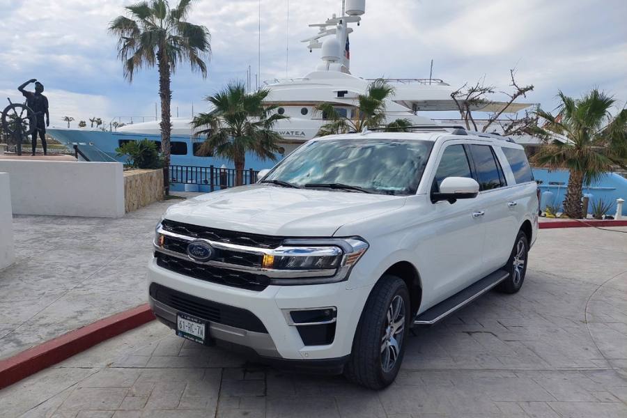 SUV Ford blanco estacionado frente a un puerto deportivo.
